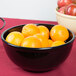 A black Cal-Mil melamine bowl filled with oranges.