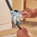 A person's hands fixing a Lift-All polyester tie-down strap with open hook.