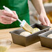 A person using an Ateco boar bristle brush to brush a loaf of bread.