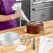 A person using an Ateco pastry bag to decorate a cake.