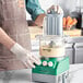 A man in a green apron using an AvaMix food processor on a counter.