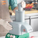 A person using an AvaMix continuous feed attachment on a grey food processor.