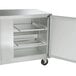 A silver metal Traulsen undercounter freezer with left and right hinged doors open.