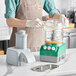 A person in an apron using an AvaMix Cadet combination food processor on a kitchen counter.