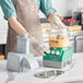 A woman in an apron setting up an AvaMix Cadet food processor on a kitchen counter.