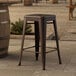 A Lancaster Table & Seating copper backless stool on a stone surface.