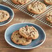 A plate of Root Nine Baking Co. vegan chocolate chunk cookies on a wood table.