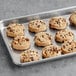 A tray of Root Nine Baking Co. vegan chocolate chunk cookies with a bite taken out of one.