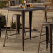 A Lancaster Table & Seating copper bar height table with glasses of beer on it on an outdoor patio.