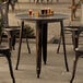 A Lancaster Table & Seating outdoor table and chairs on a stone patio with glasses of beer on it.