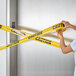 A woman's arm holding a yellow and black Xpose Safety "Caution" tape.