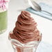 A glass bowl of Galliker's chocolate soft serve ice cream with a spoon.