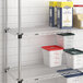 A Metro Super Erecta chrome wire shelf with white and green containers on it.