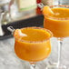 Two glasses of Perfect Puree Mandarin / Tangerine liquid with a slice of orange on the rim.