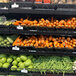 A black universal perforated metal shelf with vegetables and fruits on it.