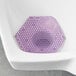 A white urinal mat with a purple hexagon in the center.