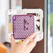 A hand holding a purple Ourfresh air freshener refill in a purple plastic container.