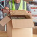 A man in a safety vest opening a 2-Piece Paper Fiber Insulated Box Liner.