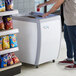 A person reaching into an Avantco custom vinyl flat top display freezer.