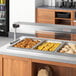ServIt Sneeze Guard Set for 60" Lighted Strip Warmers on a buffet counter with food.