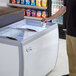 A person holding a container of ice cream in an Avantco custom vinyl flat top display freezer.