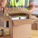 A person in a vest opens a 2-piece paper fiber insulated box liner.