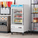 An Avantco white merchandiser refrigerator with glass doors full of drinks.