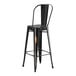 A black metal bar stool with a backrest at a Lancaster Table & Seating outdoor table.