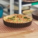 A quiche in a Gobel round fluted deep tart pan on a cooling rack.