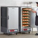 A man standing in front of a large gray Metro C5 heated holding cabinet with bread inside.