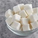 A bowl of Domino sugar cubes on a table.