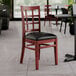 A Lancaster Table & Seating mahogany wood chair with black vinyl seat.