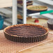 A chocolate tart in a Gobel round fluted metal pan with removable bottom.