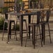 A Lancaster Table & Seating bar height outdoor table with 4 chairs and drinks on it.