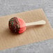 A Coco Bakery strawberry macaron pop on a stick.