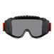 A close-up of Ergodyne Skullerz MODI safety goggles with a gray frame and orange and black straps.