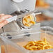 A hand using a knife to cut pasta dough on a counter.