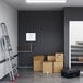 A white room with a ladder next to a box with a black case and a label on it.