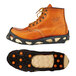 A medium brown boot with orange and black Ergodyne ice cleats on the bottom.