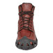 A brown shoe with a black ice cleat on the bottom.