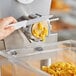 A hand using a knife to cut pasta in a pasta machine.