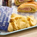 A plate of food with a sandwich and Nantucket Crisps Madaket Sweet Onion Potato Chips on it.
