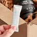 A person's hand holding a white package with blue text and a Clariant Desi Pak 11 gram bentonite clay desiccant packet.