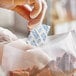 A hand in a clear plastic glove putting a Clariant Oxy-Guard oxygen absorber packet into a bag of food.