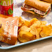 A plate with a sandwich, Nantucket Crisps Cisco Beach BBQ Potato Chips, and a can of water.