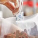 A person in a clear glove using a Clariant Oxy-Guard oxygen absorber to package food.