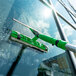 An Unger VisaVersa Pro 2-in-1 Microfiber Window Washer with green squeegee cleaning a window.