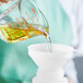 A hand pouring Mazola Corn Oil into a measuring cup.