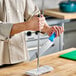 A person holding a knife on a cutting board using a Choice stainless steel sharpening rod.