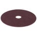 A maroon circular Scrubble conditioning floor pad with a hole in the middle.